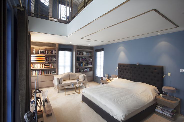 a bedroom with blue walls and white carpeted flooring has a large bed in the middle