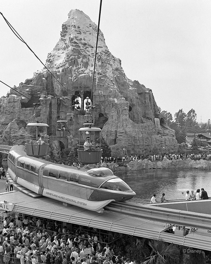 a crowd of people standing around a train on top of a bridge