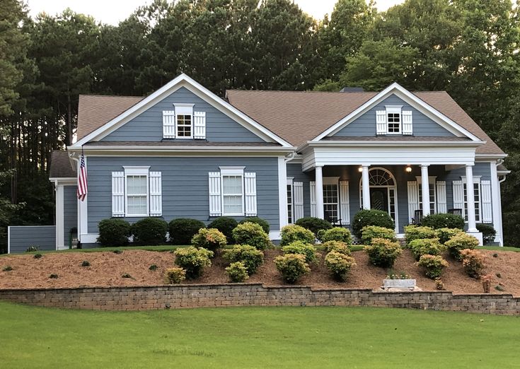 a blue house with white shutters and trees in the background