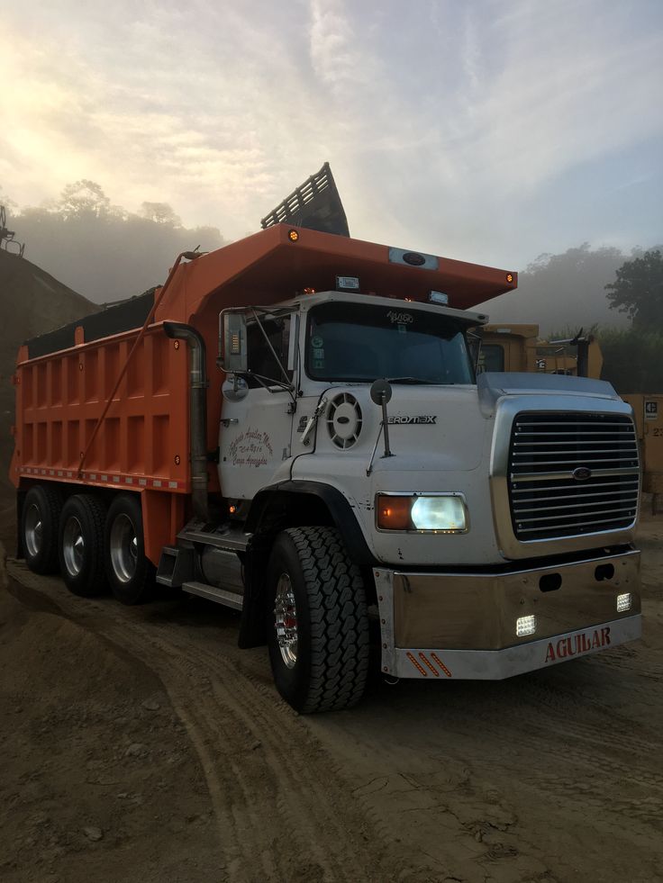 a dump truck parked on the side of a dirt road