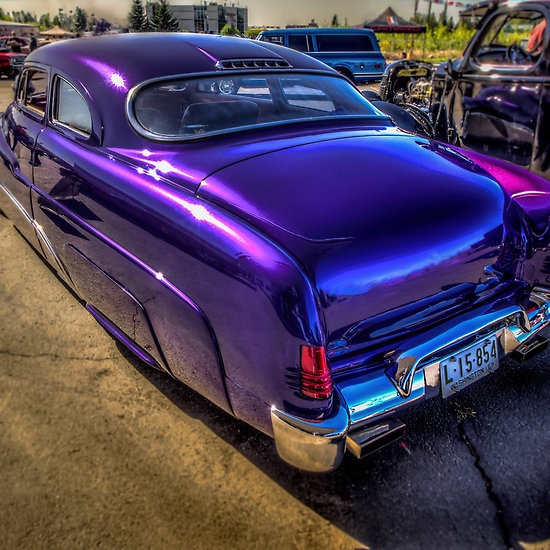 an old purple car parked in a parking lot