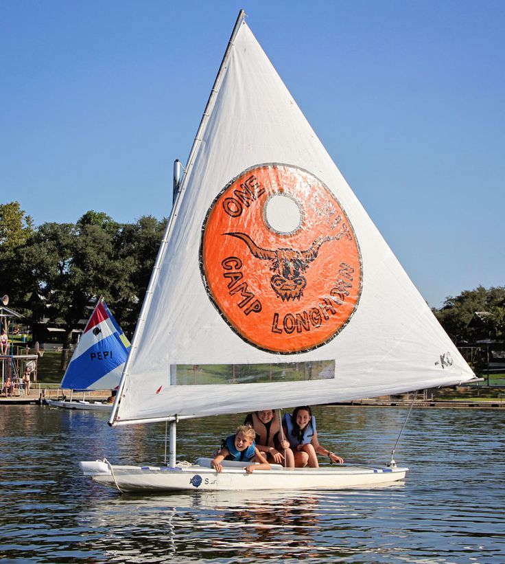 two people and a child on a small sailboat