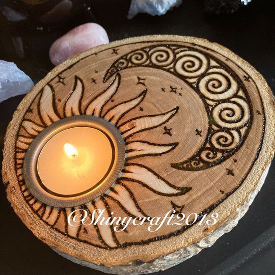 a candle is sitting on top of a wooden plate with a sun and moon design