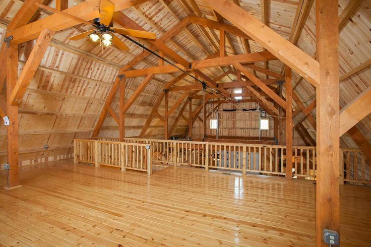 an empty room with wooden floors and ceiling fan in the center, surrounded by wood beams