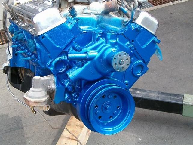 a blue engine is sitting on a piece of wood