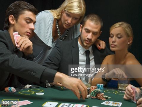 a group of people playing cards at a casino table with one man in the middle