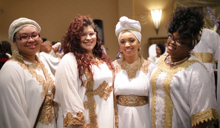 three women dressed in white and gold standing next to each other