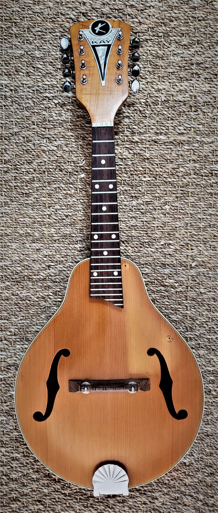 an old guitar is hanging on the wall in front of a wicker basket background