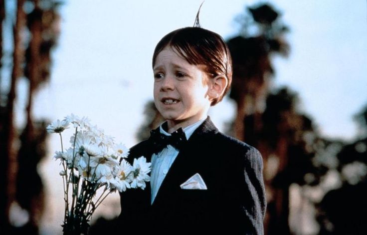 a young boy in a tuxedo holding flowers