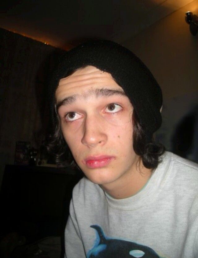 a young man wearing a black beanie looking at the camera with an angry look on his face