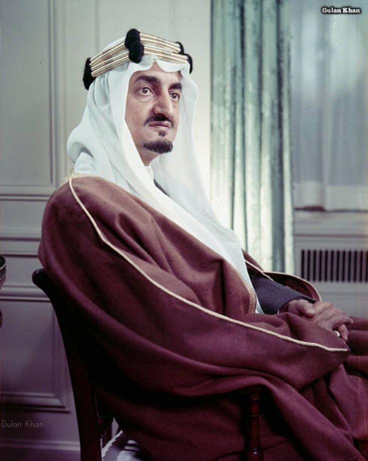 an old photo of a man wearing a headdress and sitting in a chair