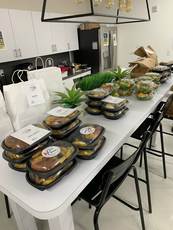 a table filled with lots of food sitting on top of a white counter next to chairs