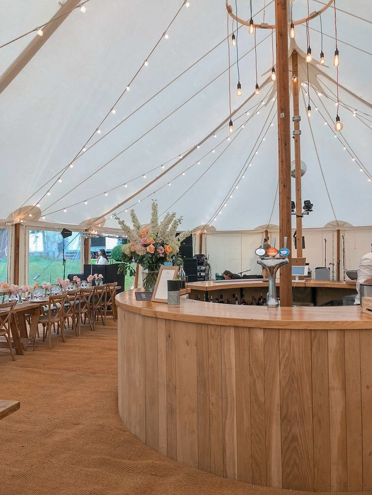 the inside of a tent with tables, chairs and lights on it's ceiling