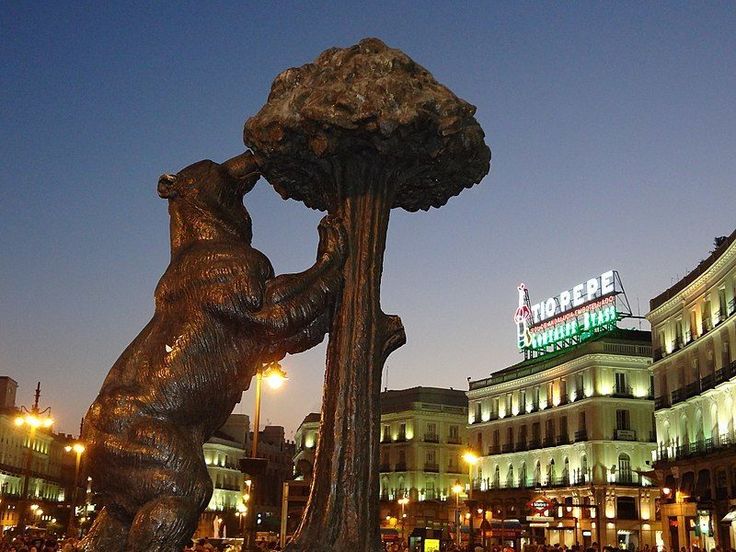 a statue of a bear holding onto a tree in front of a building at night