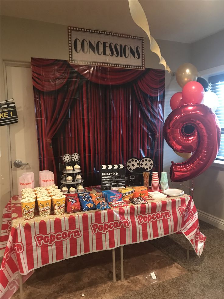 a red and white table topped with lots of cupcakes next to a curtain