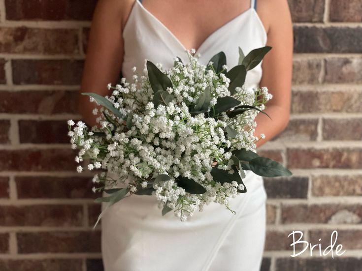 a woman in a white dress holding a bouquet of baby's breathflowers