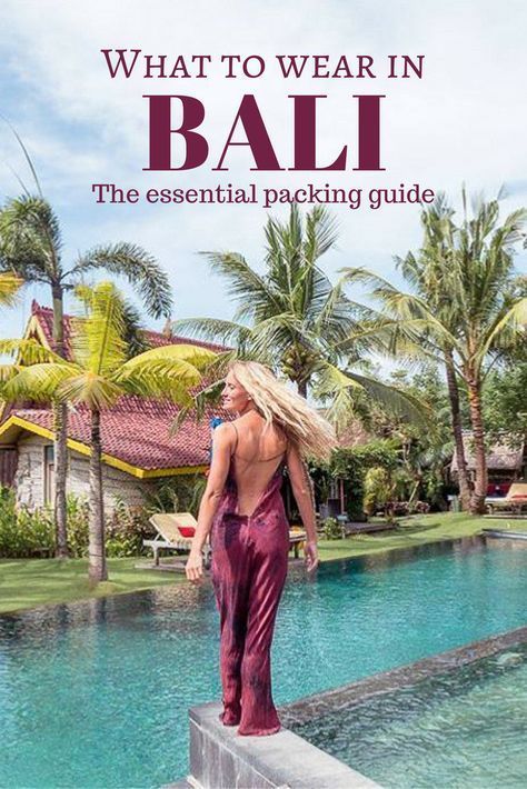 a woman standing on the edge of a swimming pool with palm trees in the background