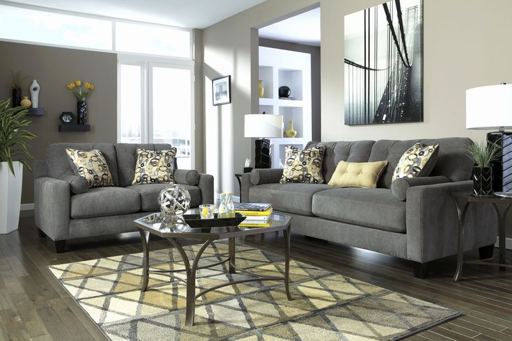 a living room filled with gray couches and pillows