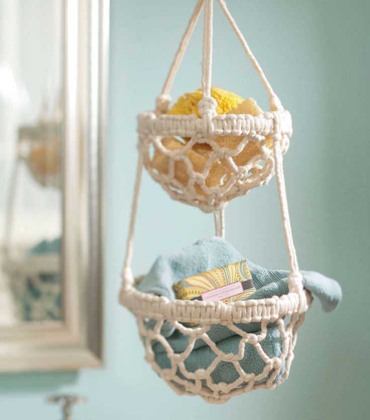 two hanging baskets filled with towels and other items in a bathroom area next to a mirror