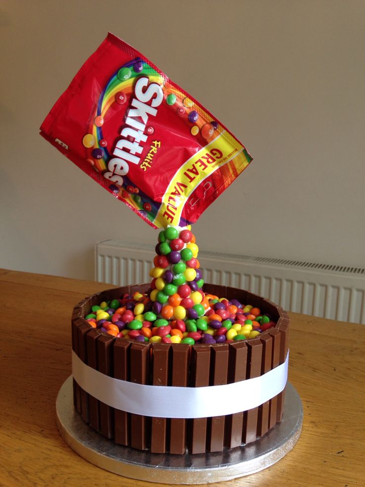 a chocolate cake with candy on top and a bag of skittles sticking out of it