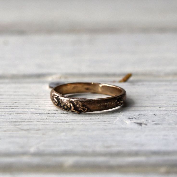 a gold wedding ring sitting on top of a white wooden table next to an orange peel