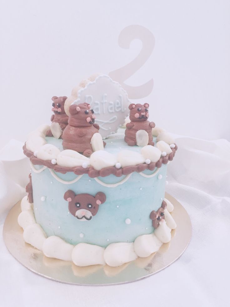 a two tiered cake with teddy bears on top and the number 2 in the middle