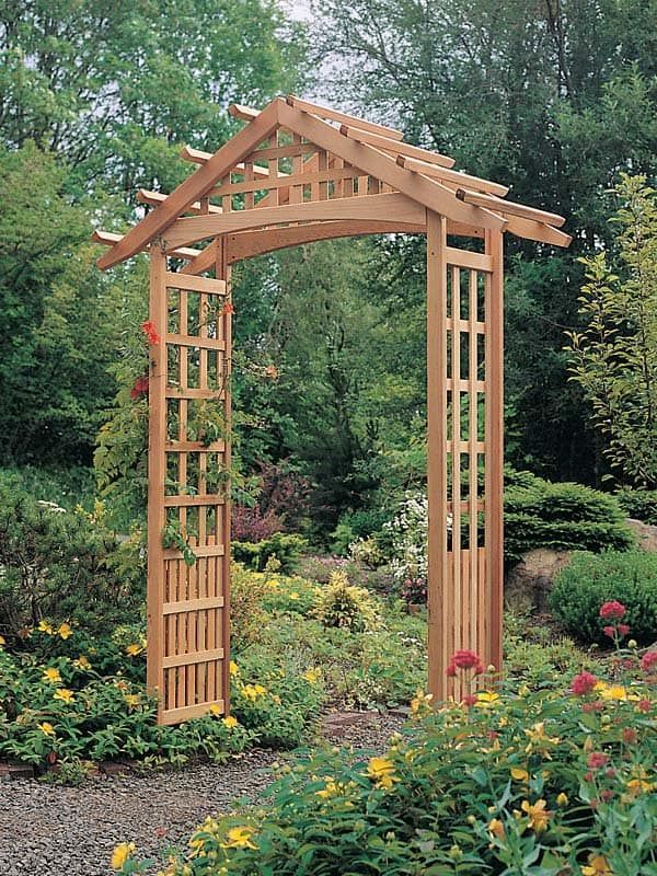 a wooden arbor in a garden surrounded by flowers