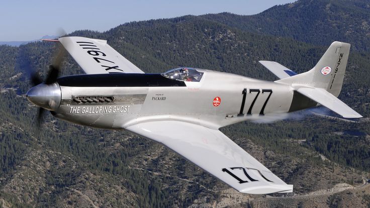 an airplane flying in the air with mountains in the background