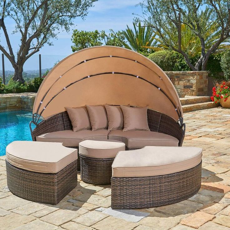 an outdoor patio furniture set with cushions and tables next to a swimming pool in the background