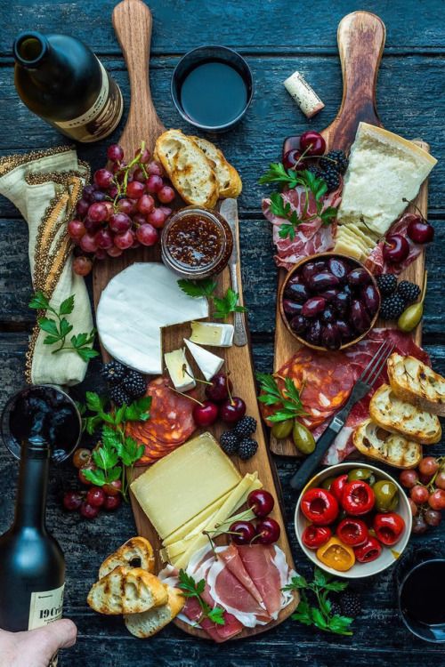 an assortment of cheeses, meats and fruit on a table