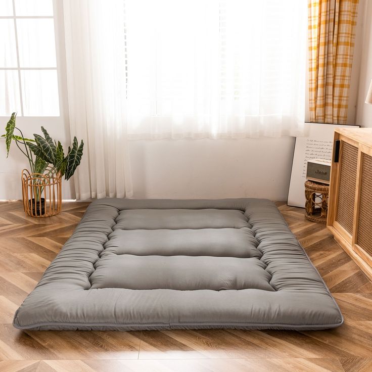 a futon mattress is sitting on the floor in front of a window