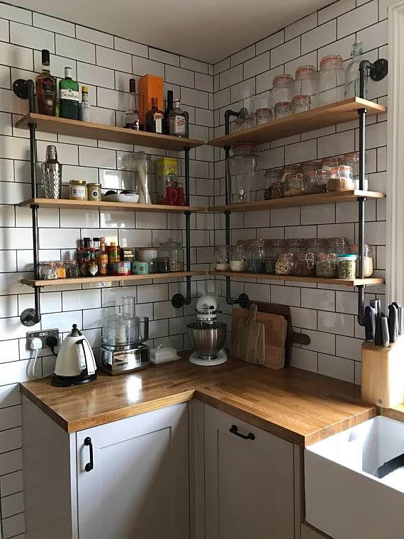 a kitchen with white tile walls and wooden counter tops, open shelving above the sink