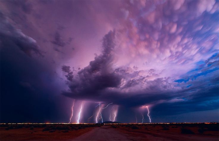 lightning strikes in the sky above a dirt road