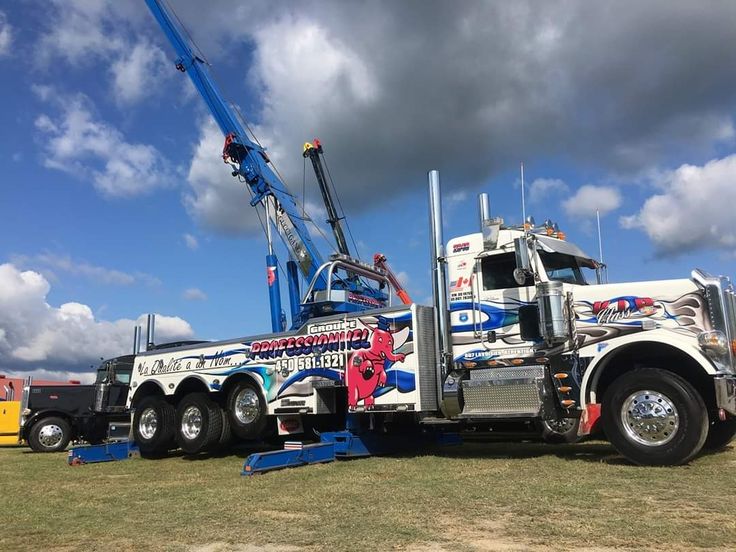 a large truck with a crane on the back of it's flatbed is parked in a field