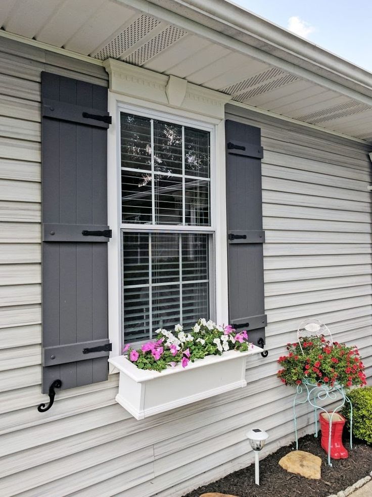 a white house with black shutters and flower boxes