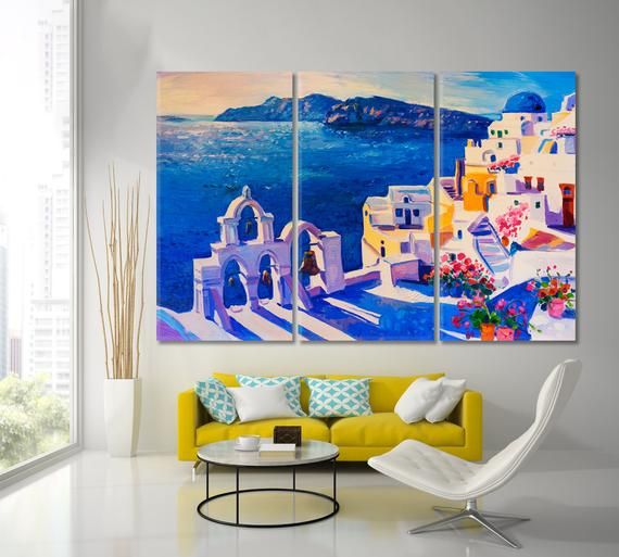 a living room with three paintings on the wall and a yellow couch in front of it