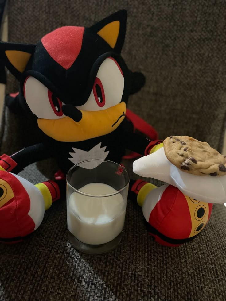 a stuffed animal is sitting next to a glass of milk and cookie on a chair