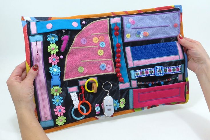 a person holding up a colorful purse with lots of items on it, including scissors and other things