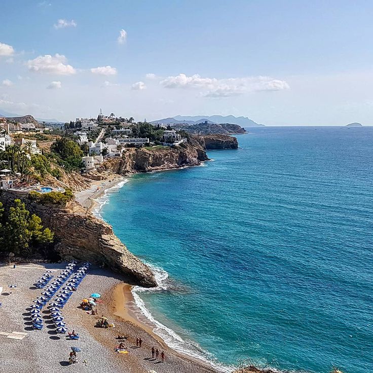 an aerial view of a beach with umbrellas and chairs on the sand near the water