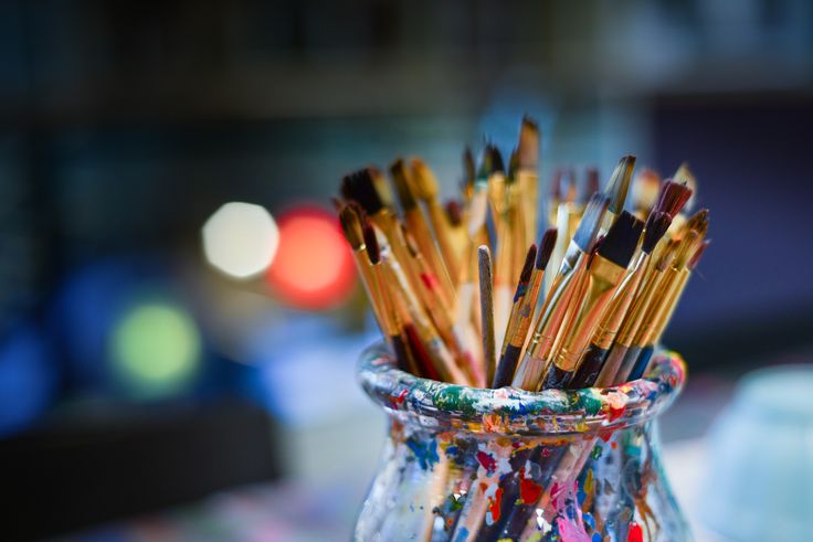 a glass vase filled with lots of paint brushes