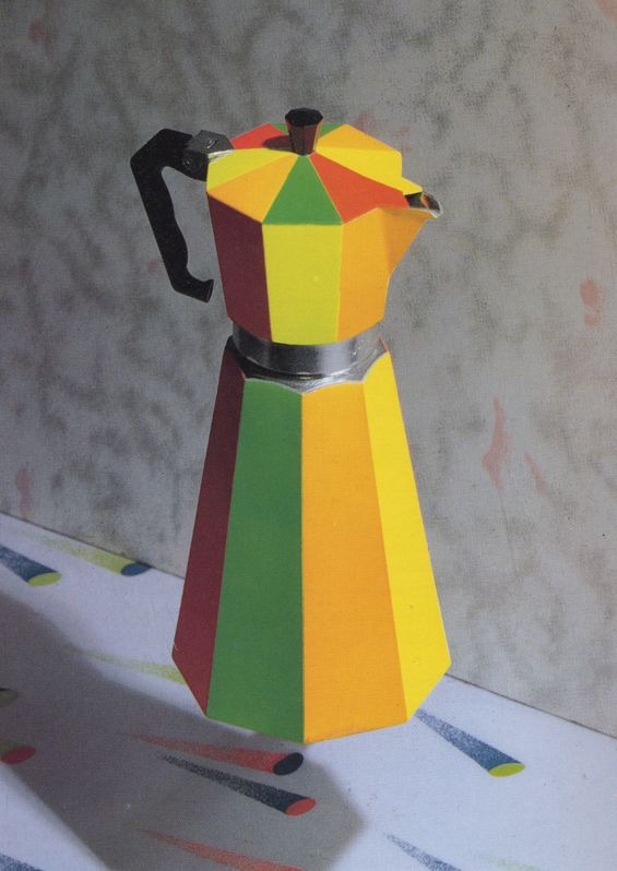 a multicolored paper coffee pot sitting on top of a table next to a wall