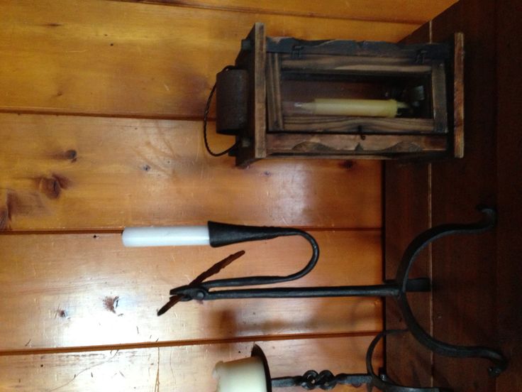 an old fashioned wall light hanging on the side of a wooden wall next to a candle holder