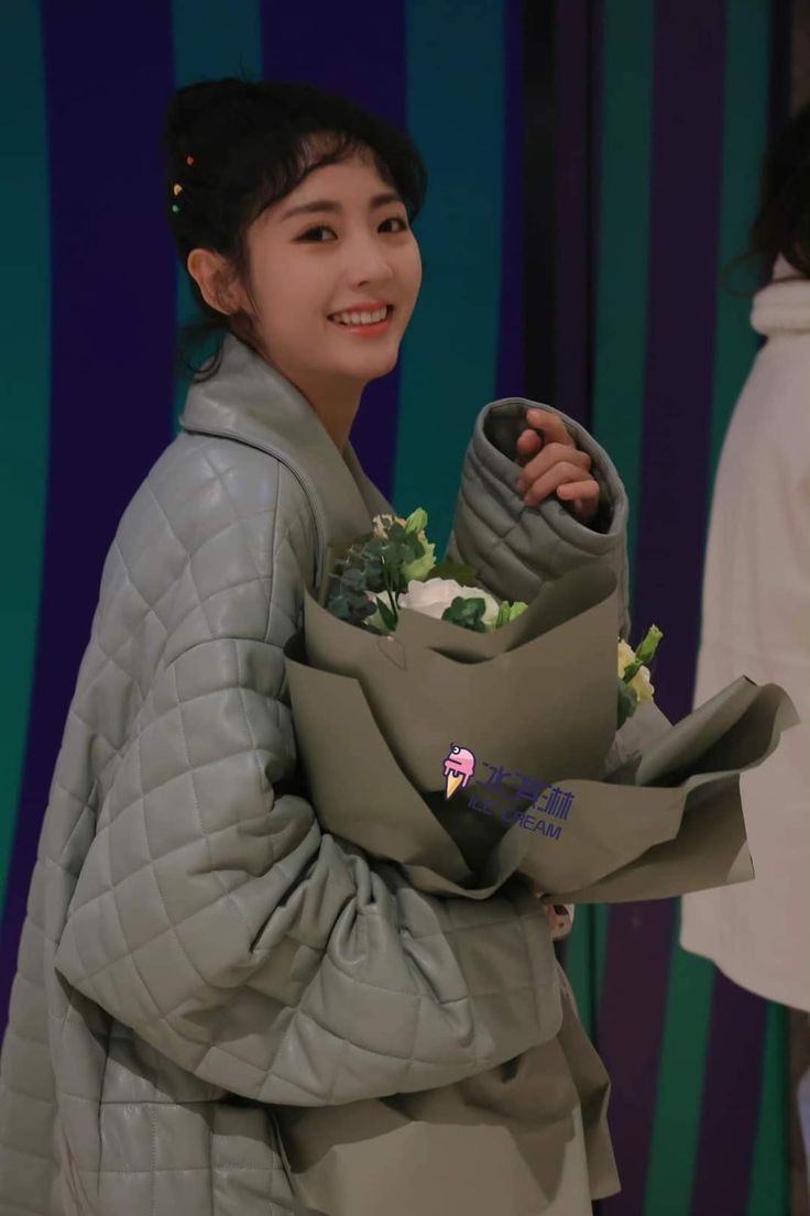 a young woman is holding a bag with flowers in it and smiling at the camera