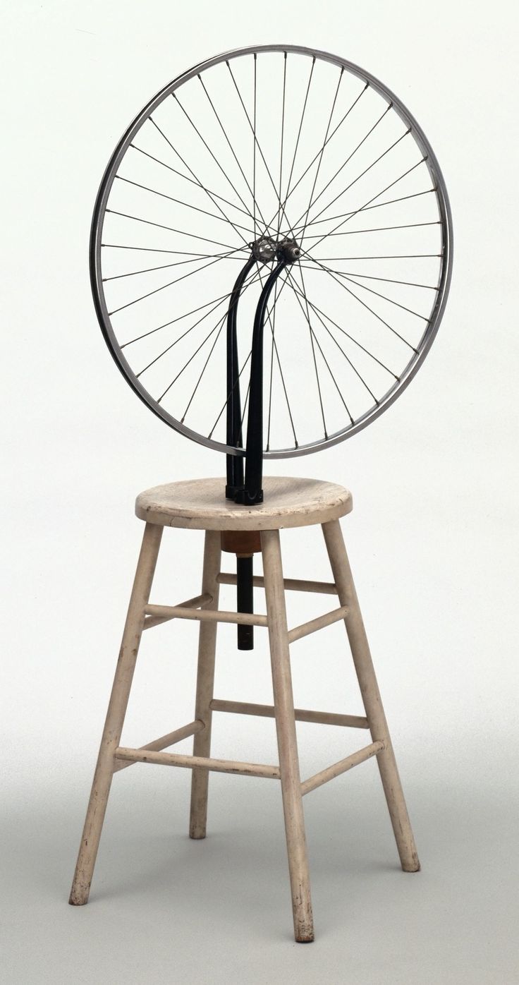 an old fashioned spinning wheel on top of a wooden stool with a black and white background