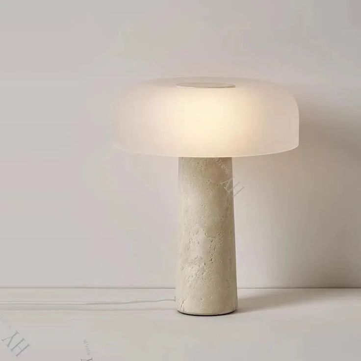 a white lamp sitting on top of a table next to a light bulb in the shape of a mushroom