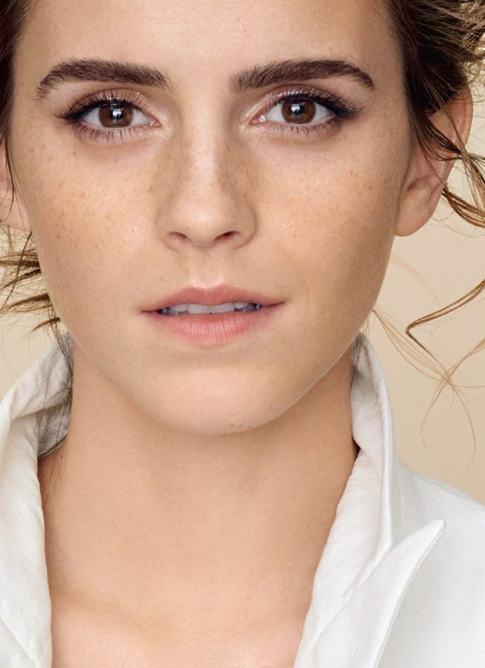 a woman with freckled hair and blue eyes wearing a white shirt is looking at the camera