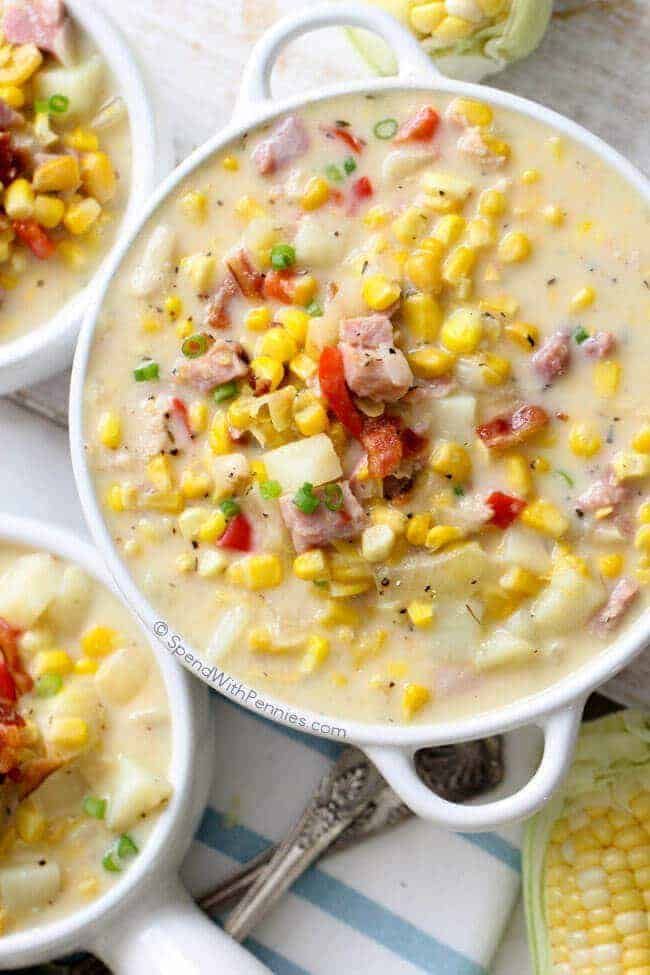 three white bowls filled with corn chowee on top of a table