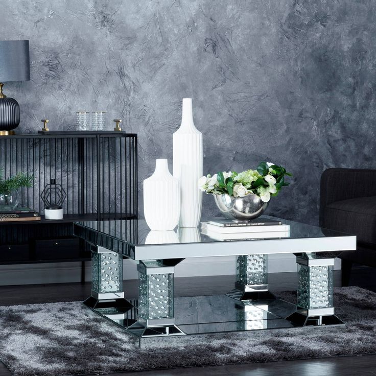 a modern living room with black and white decor on the walls, silver furniture and flowers in vases