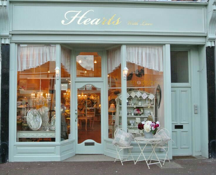 a store front with two chairs and a table in front of the window that says hearts