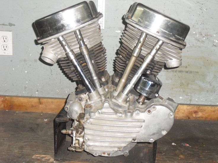 an old motorcycle engine sitting on top of a wooden floor next to a gray wall